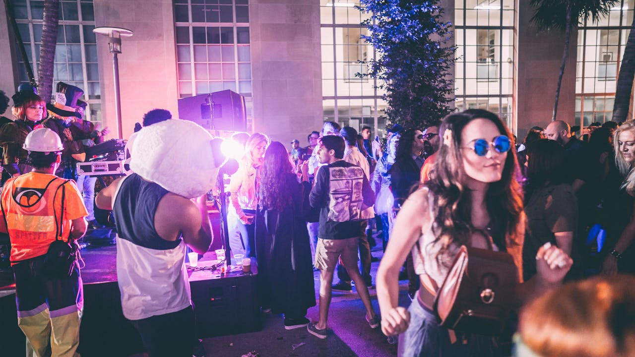 Home Festive outdoor party in Miami featuring energetic crowd and vivid lights.